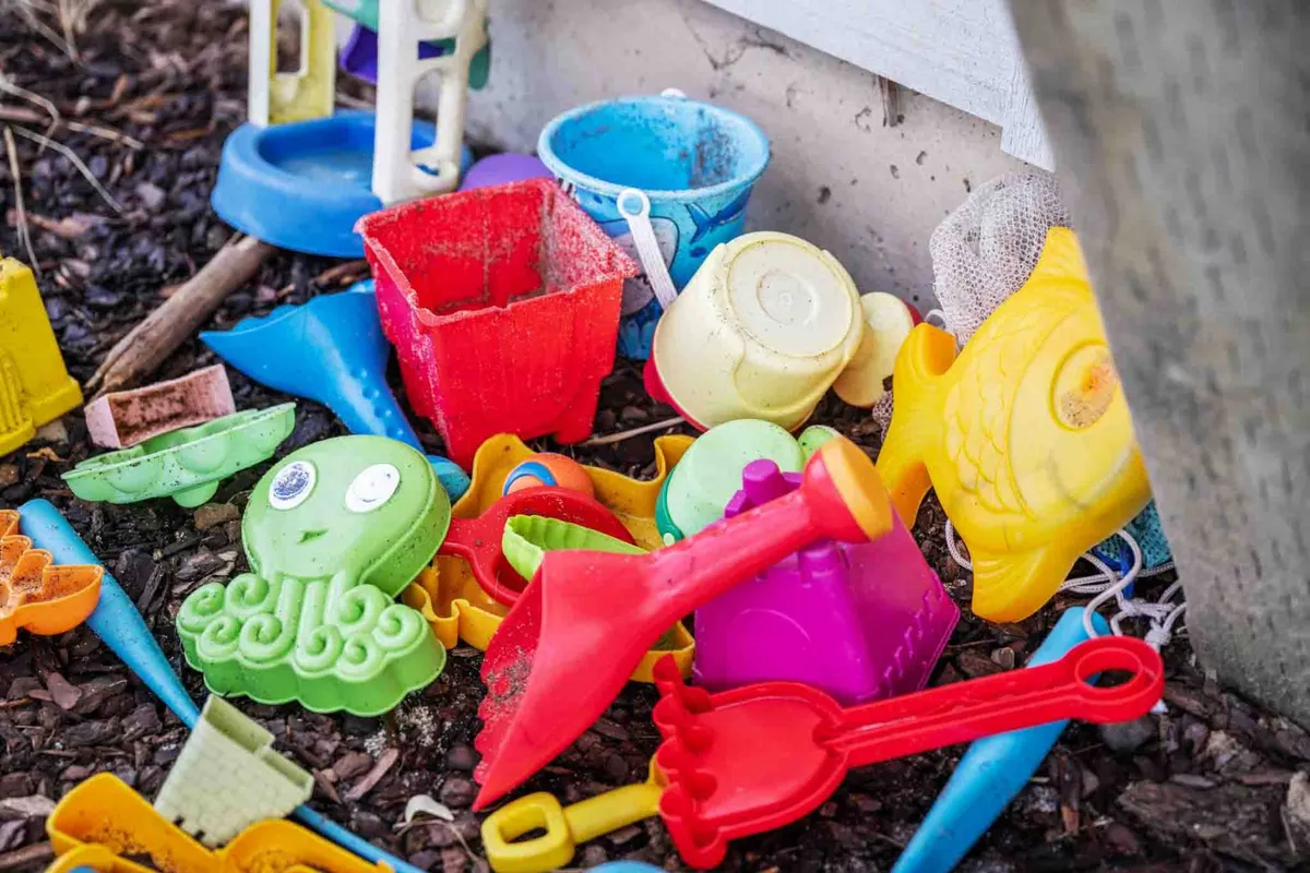 A playful exterior shot captures colorful plastic toys scattered on dirt and mulch, hinting at family-friendly spaces where children and pets alike can play and explore. The whimsical mood underscores the home’s welcoming environment for all ages—and species.